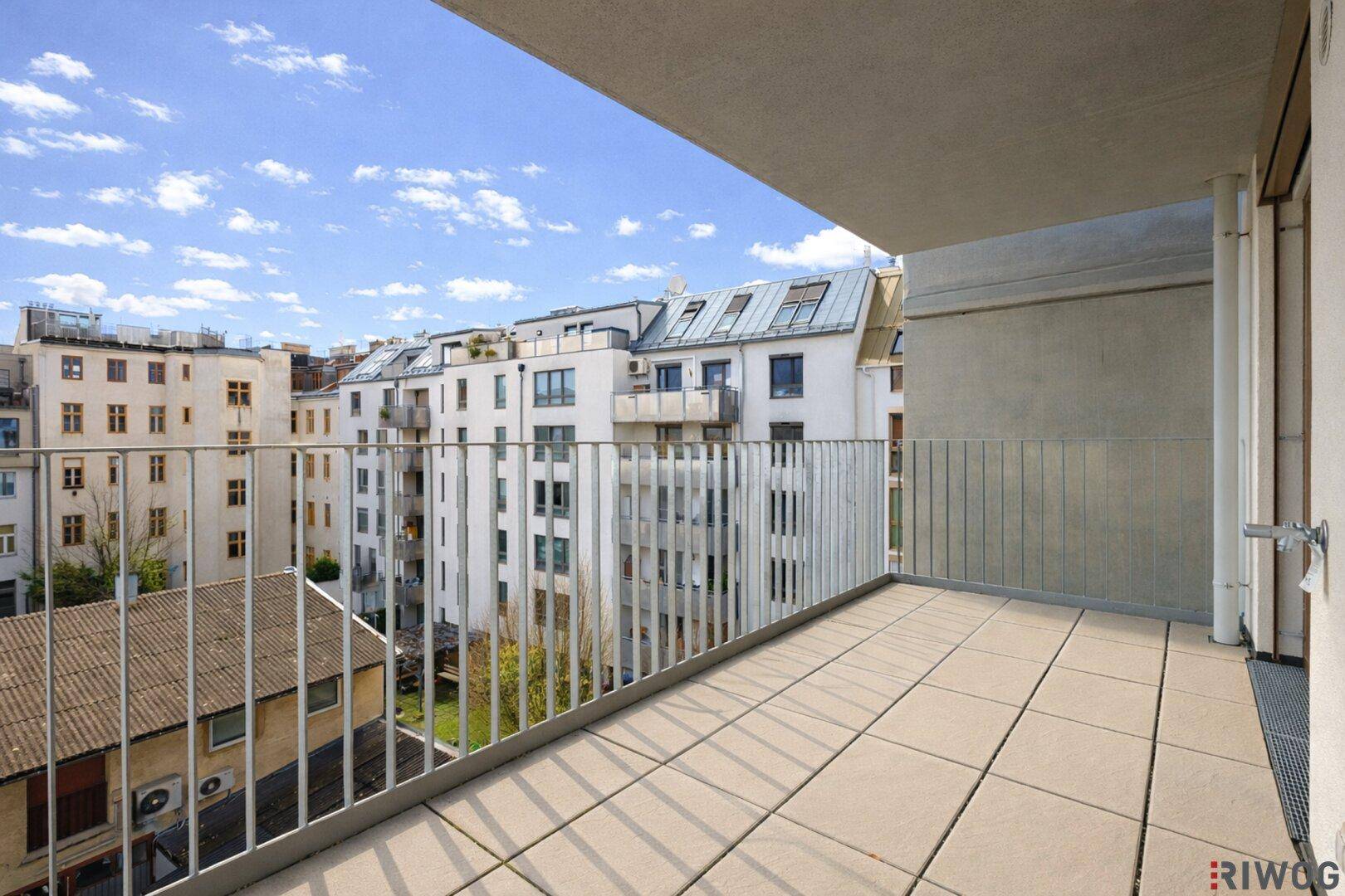 Geräumiger Balkon mit Fliesenboden und Metallgeländer, bietet Platz für individuelle Gestaltung.