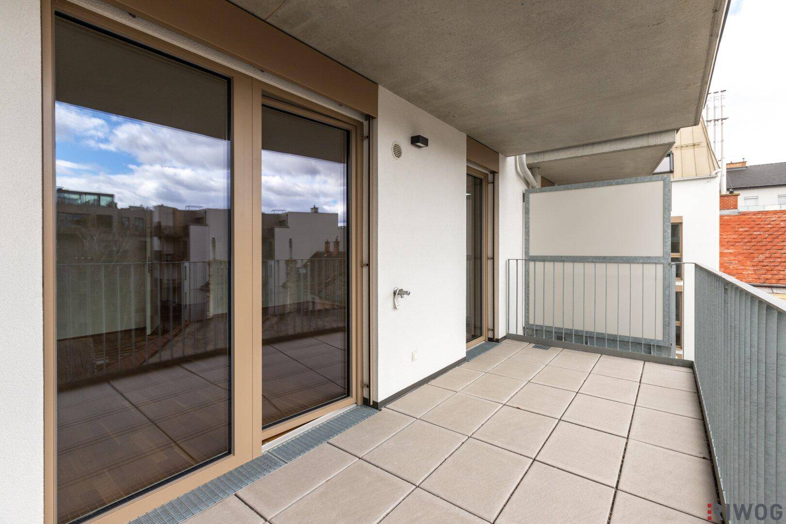 Heller Balkon mit Fliesenboden und Blick auf die Umgebung, bietet Platz für Entspannung im Freien.