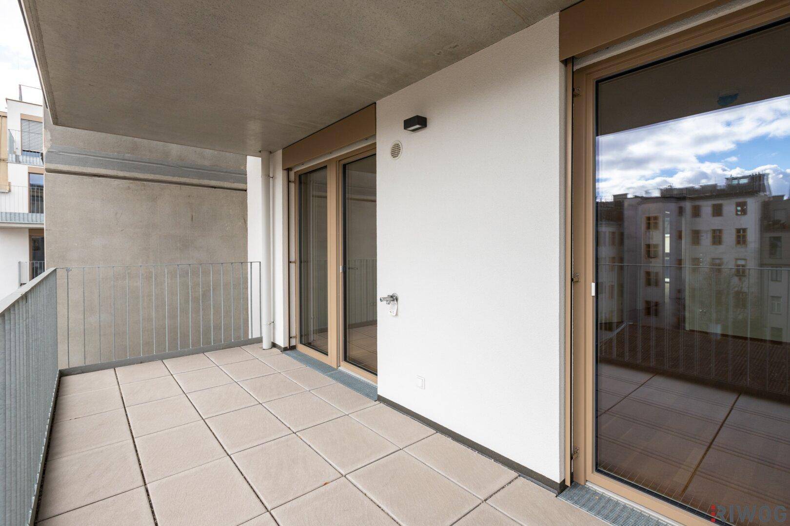 Geräumiger Balkon mit Fliesenboden und Blick auf die umliegenden Gebäude, ideal für sonnige Tage.