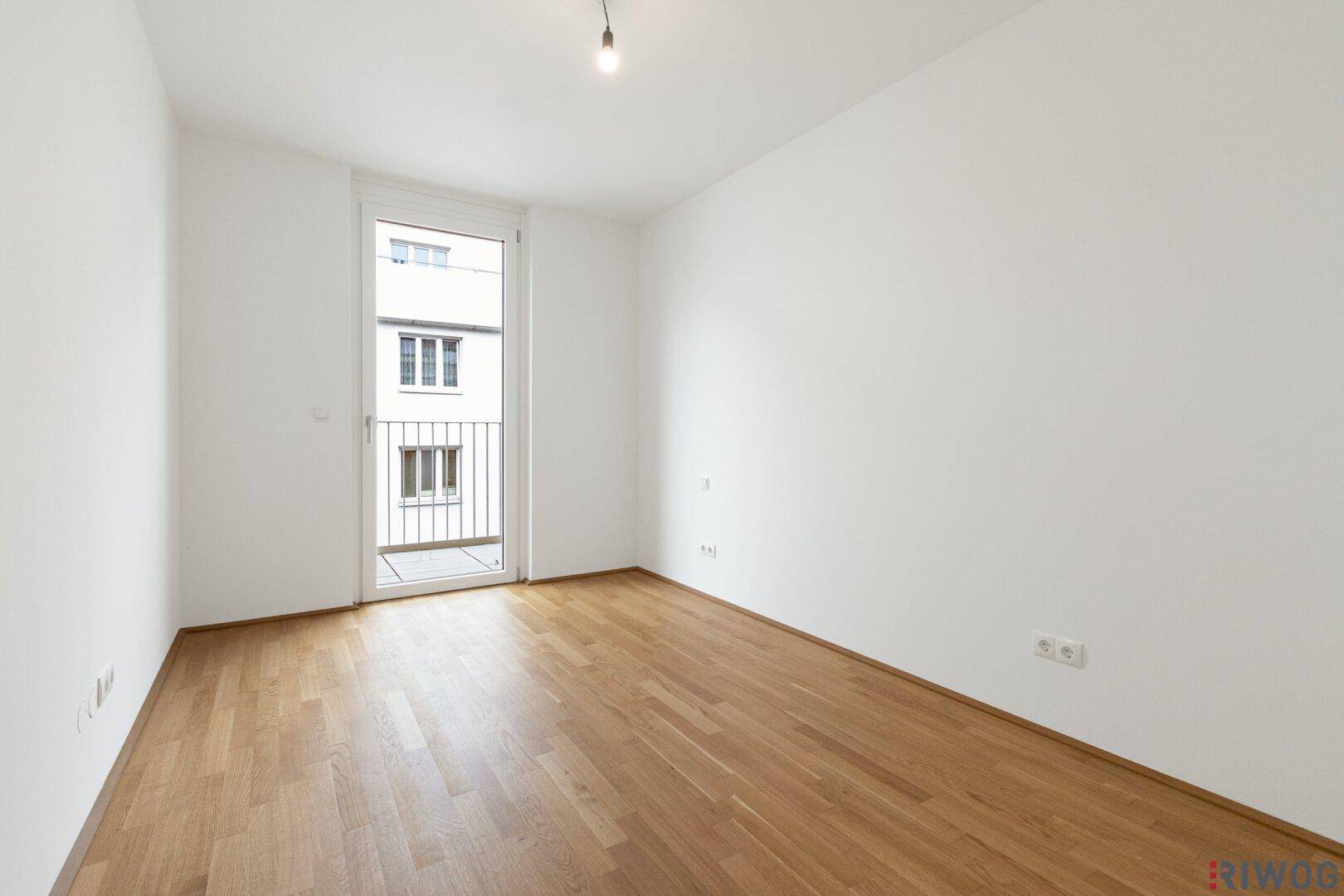 Helles Schlafzimmer mit Parkettboden und französischem Balkon, bereit zur individuellen Einrichtung.