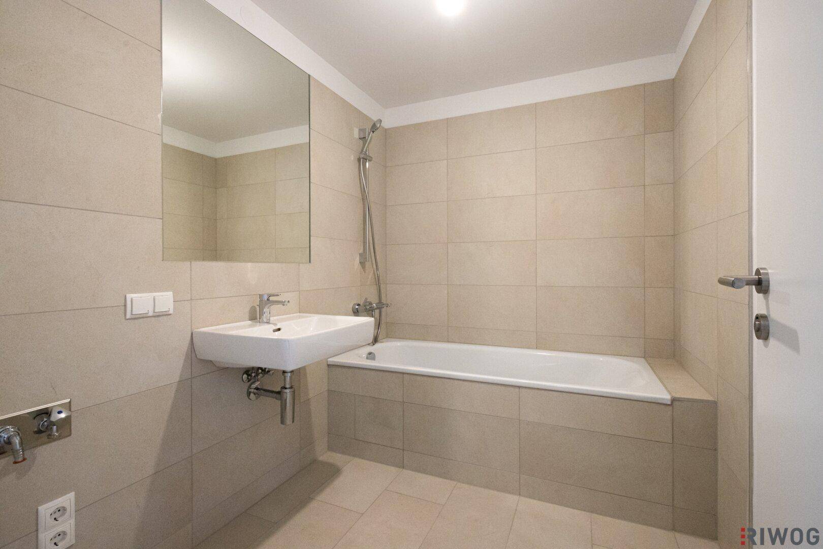 Modernes Badezimmer mit Badewanne, Waschbecken und hellen Fliesen, in sehr gutem Zustand.