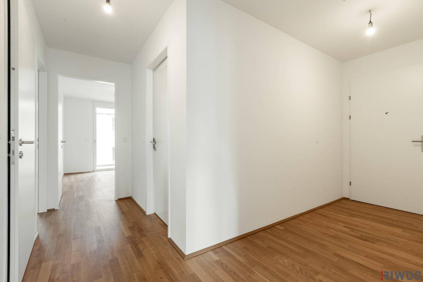 Heller Flur mit Parkettboden und weißen Türen, verbindet die verschiedenen Räume der Wohnung.