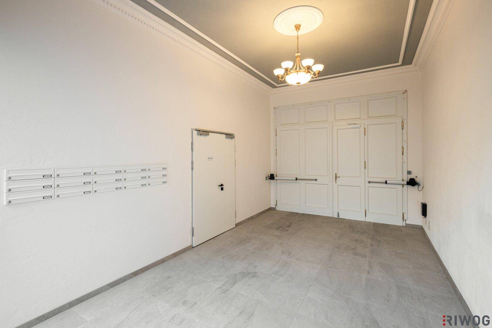Geräumiger Eingangsbereich mit Fliesenboden, Briefkästen und dekorativer Decke.