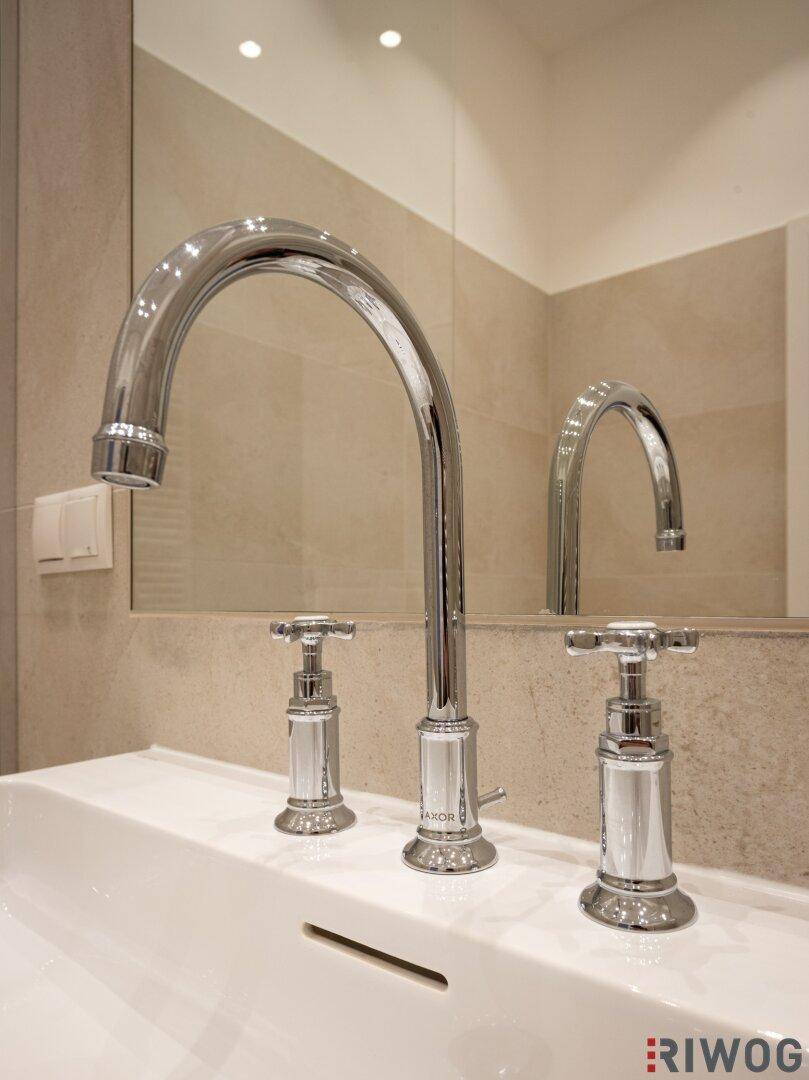 Nahaufnahme eines modernen Waschbeckens mit stilvoller Armatur und großem Spiegel im Badezimmer.