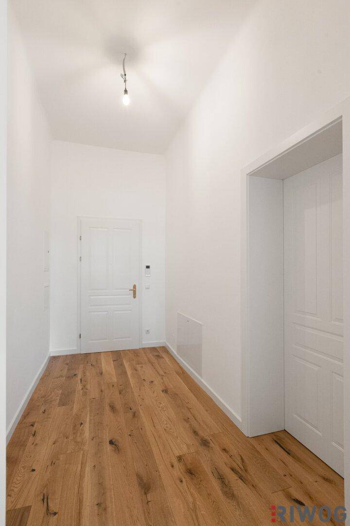 Eingangsbereich mit Holzboden und weißer Wohnungstür, hell und freundlich gestaltet.