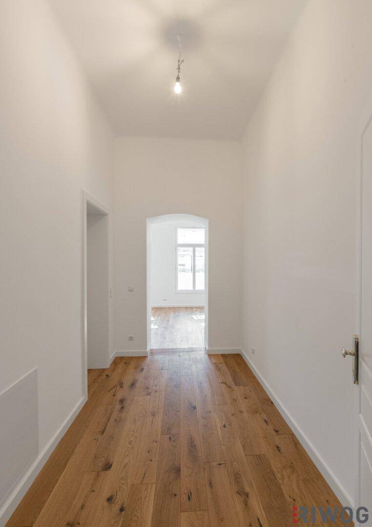 Heller Flur mit Holzboden und Durchgang zu weiteren Räumen, schafft eine einladende Atmosphäre.