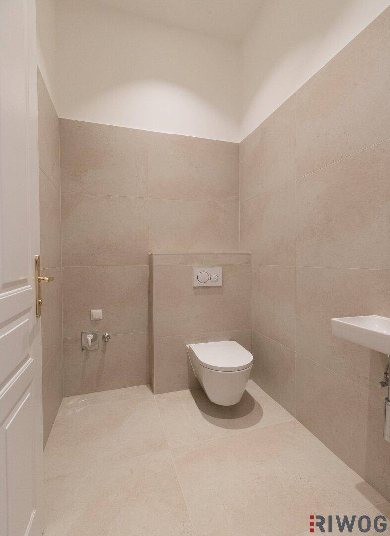 Separates WC mit wandhängender Toilette und kleinem Waschbecken, praktisch und modern gestaltet.