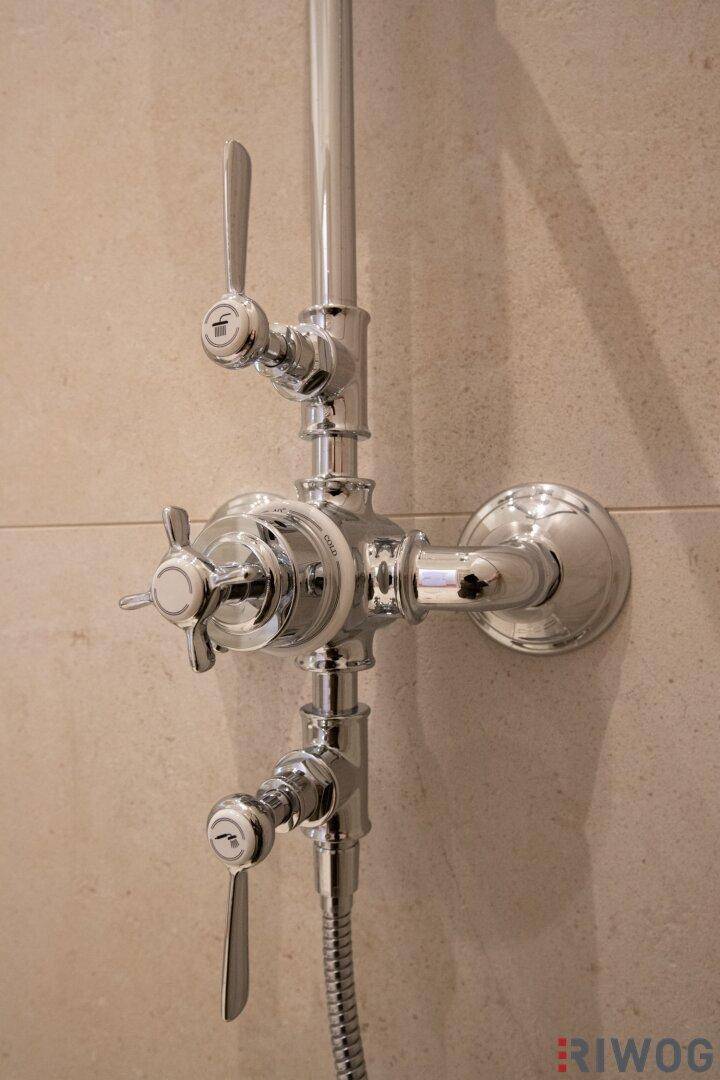Nahaufnahme der glänzenden Chrom-Armaturen einer modernen Dusche mit verschiedenen Bedienelementen.
