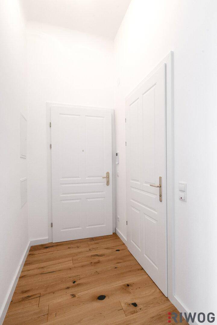 Heller Flur mit Holzboden und zwei weißen Türen, die zu den Wohnräumen führen.
