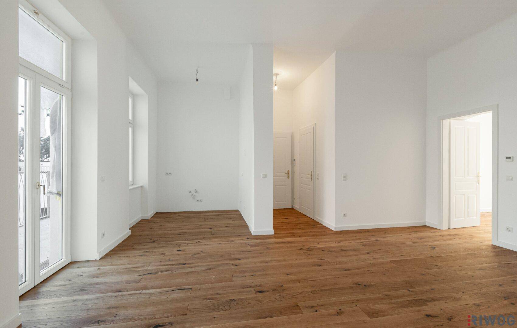 Geräumiges, helles Zimmer mit Holzboden und Zugang zu weiteren Räumen.