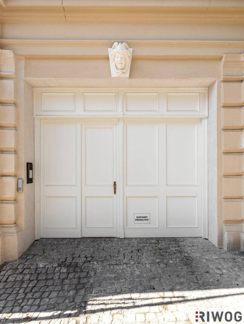 Klassisches Garagentor in Weiß mit dekorativen Elementen und Kopfsteinpflaster davor.
