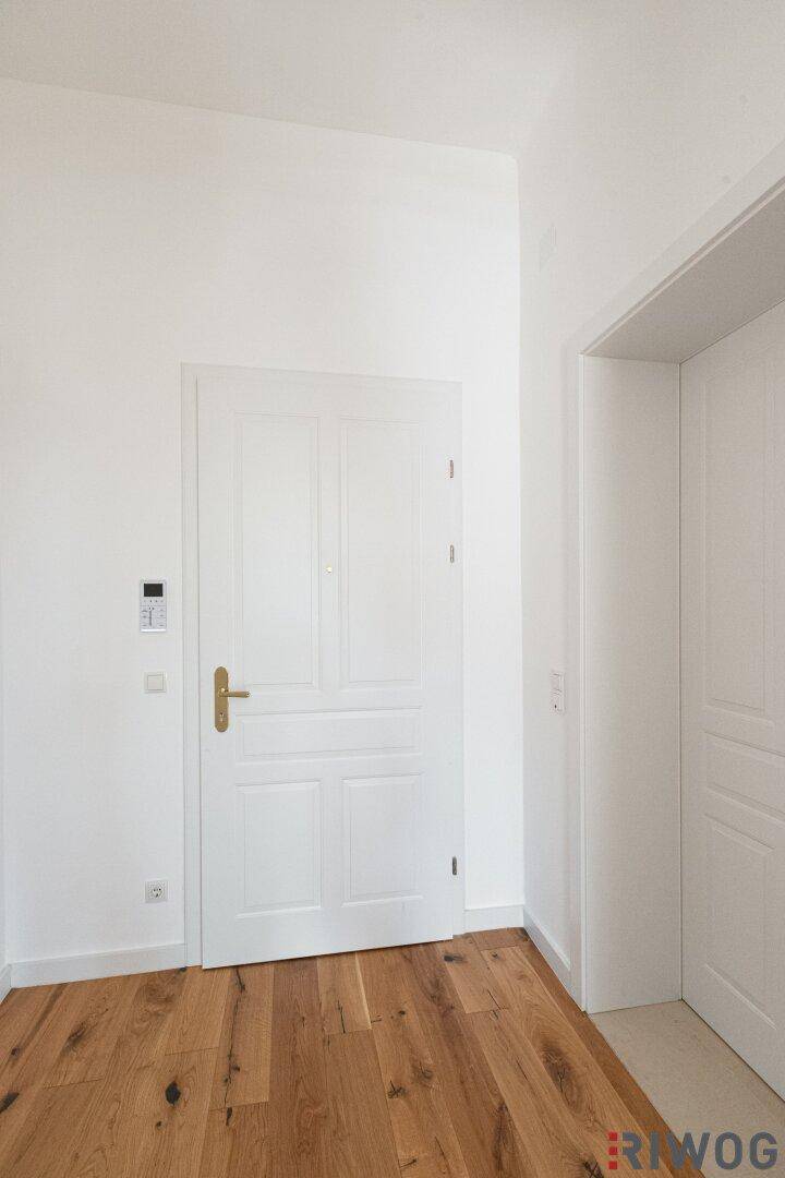 Eingangsbereich mit Holzboden und einer weißen Tür, die zu den Wohnräumen führt.