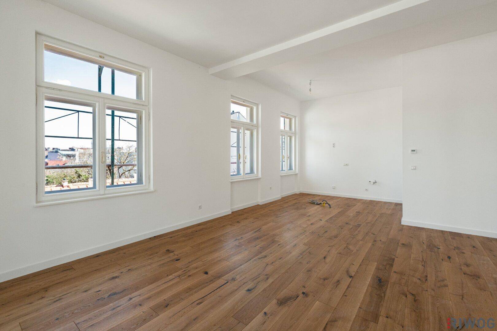 Helles, leeres Zimmer mit großen Fenstern und neuem Holzfußboden, bereit zur individuellen Gestaltung.