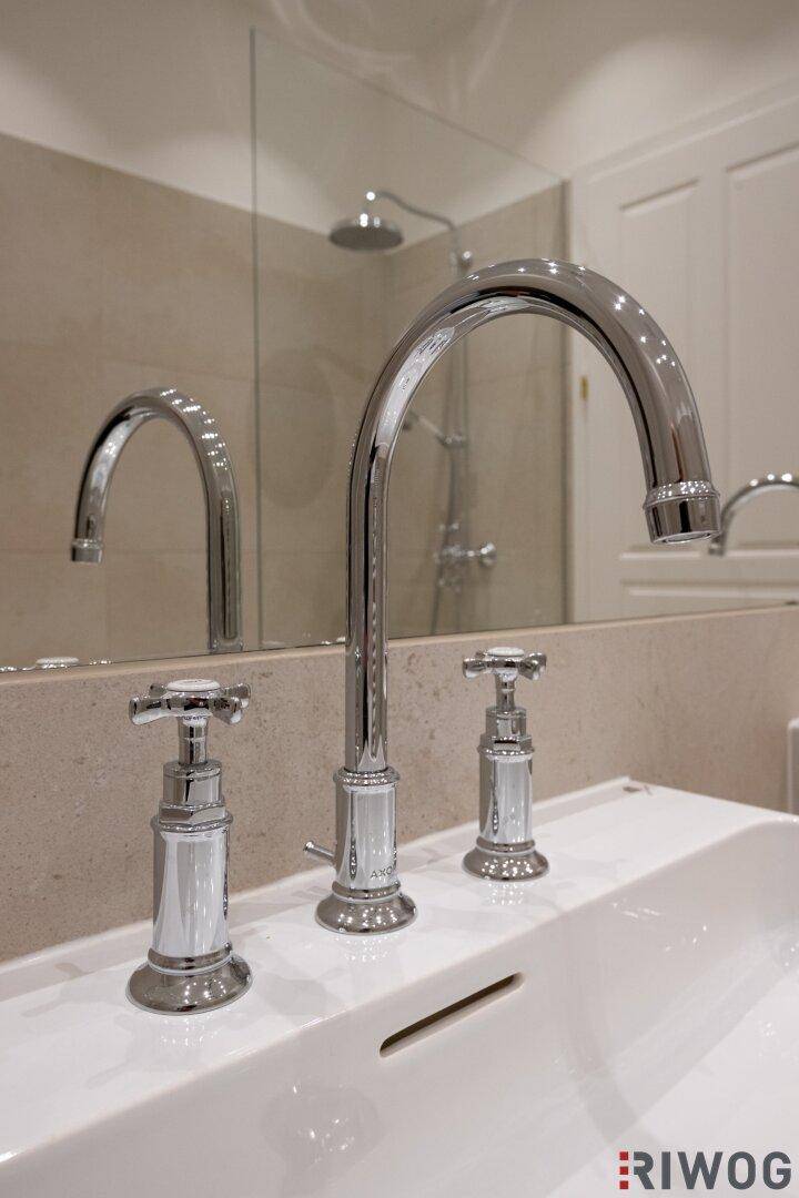 Detailaufnahme eines modernen Chrom-Wasserhahns über einem Waschbecken im Badezimmer.
