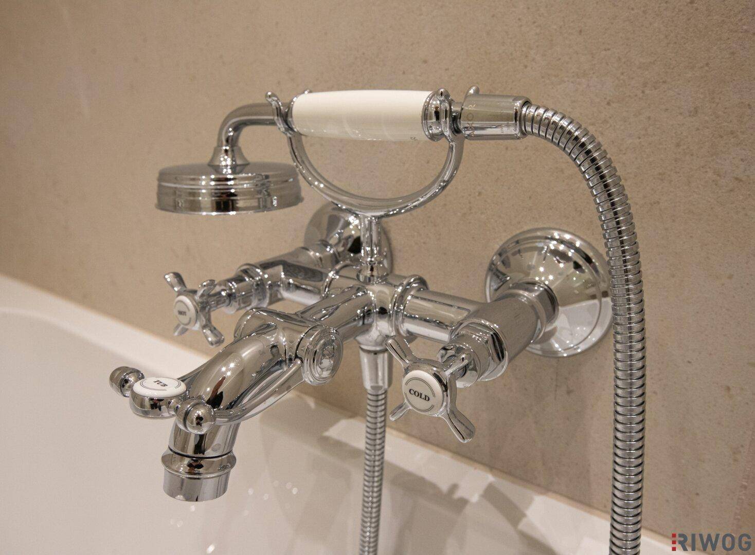 Klassischer Badewannen-Wasserhahn mit Handbrause und traditionellen Kreuzgriffen.