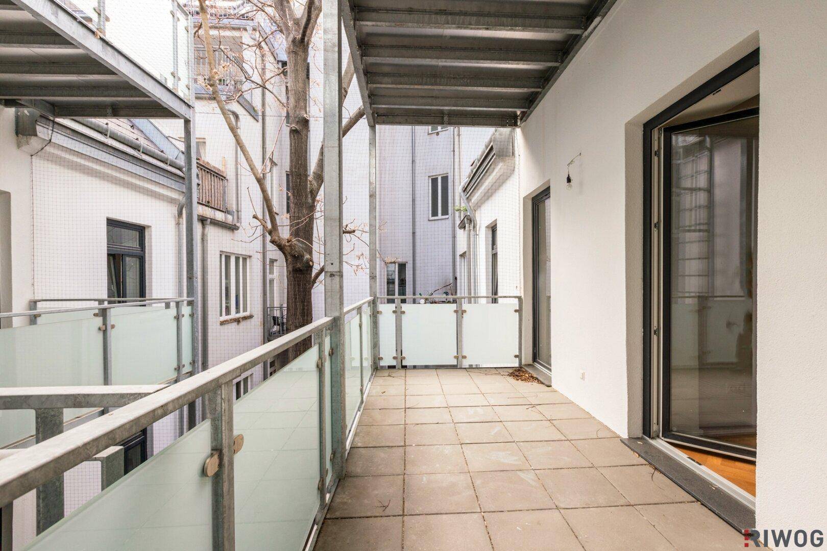 Geräumiger Balkon mit Fliesenboden und Blick in den ruhigen Innenhof.