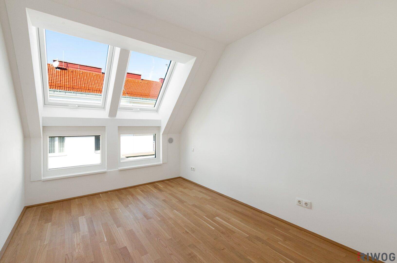Leerer Raum mit Holzboden, Dachschräge und Dachfenstern, ideal für individuelle Gestaltung.
