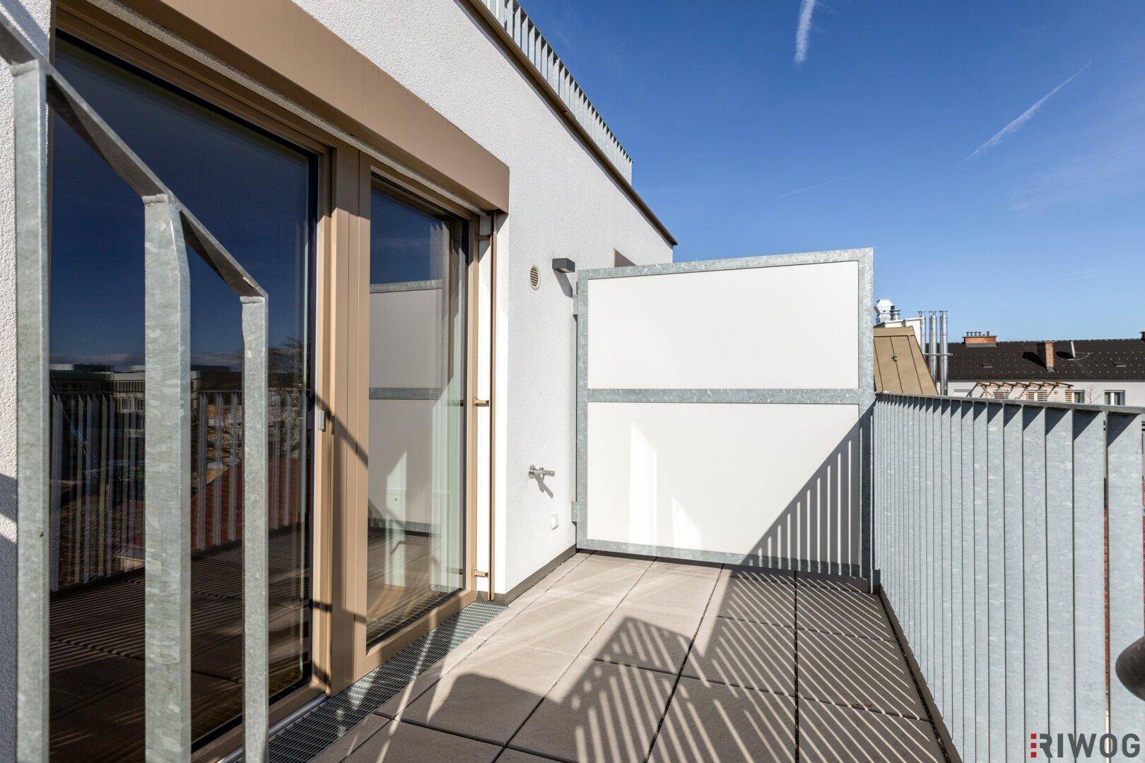 Kleiner Balkon mit Fliesenboden und Metallgeländer, ideal für einen sonnigen Morgen.