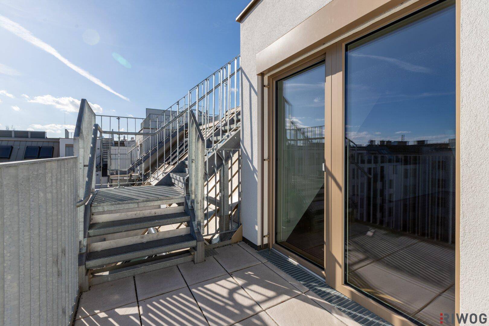 Balkon mit Zugang zu einer weiteren Ebene über eine Außentreppe und Stadtblick.