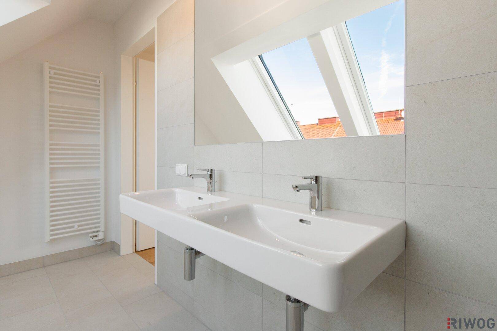 Modernes Badezimmer mit Doppelwaschbecken, großem Spiegel und Fliesenboden.