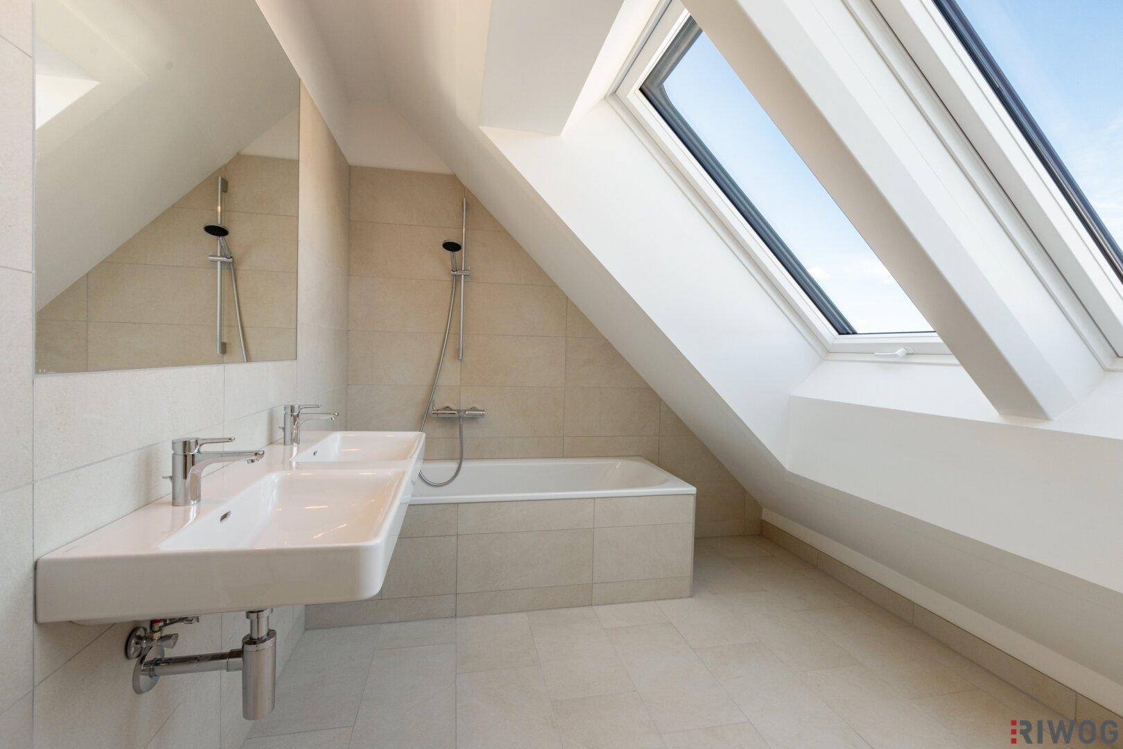 Modernes Badezimmer mit Doppelwaschbecken, Badewanne und großen Dachfenstern.