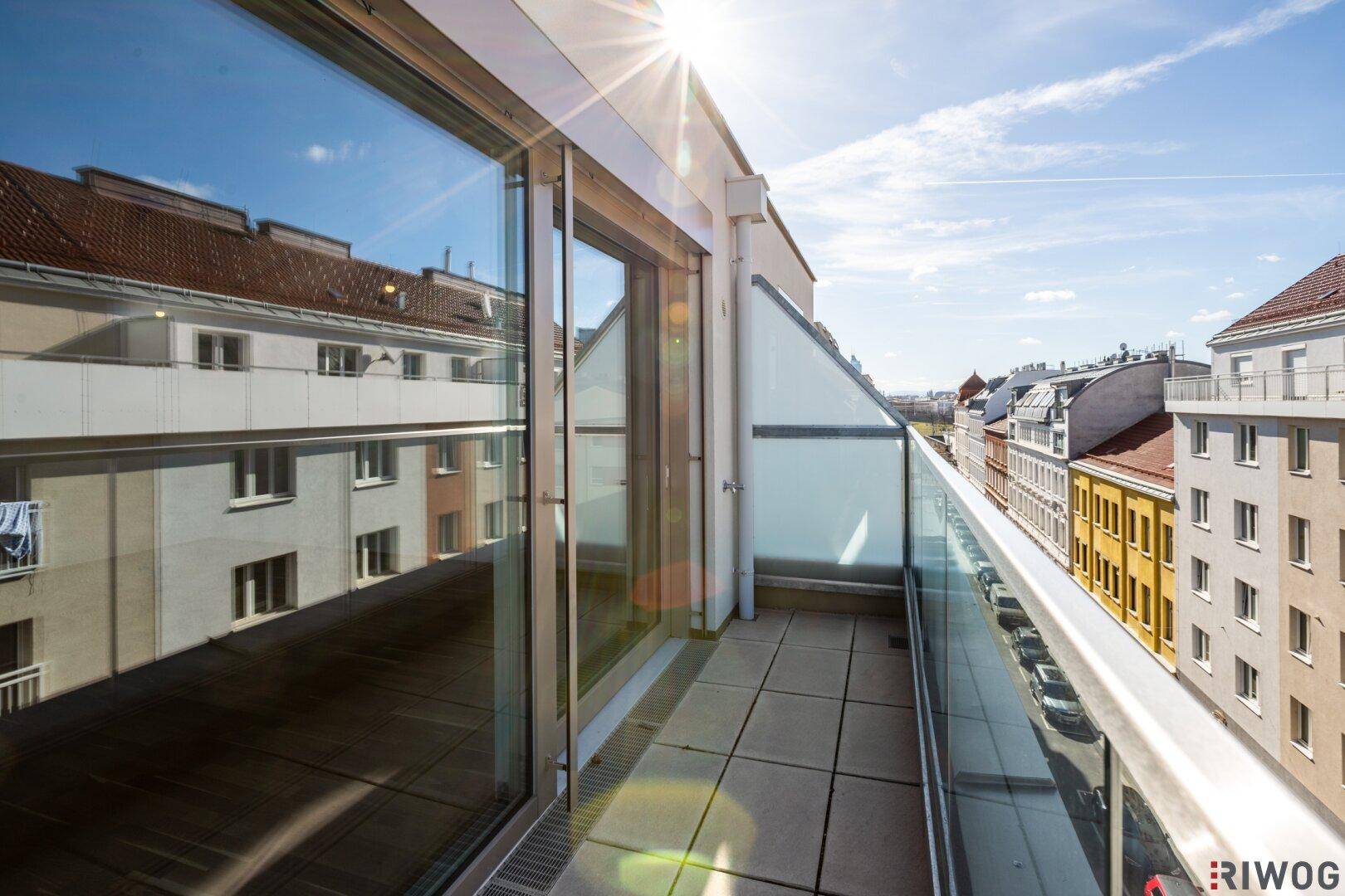 Heller Balkon mit Fliesenboden und Glasgeländer, bietet einen weiten Blick über die Stadt.