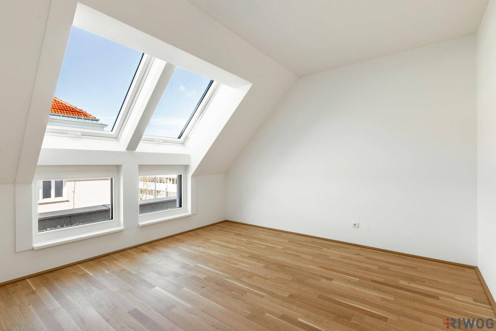 Geräumiges Dachgeschosszimmer mit Parkettboden und schrägen Wänden, ideal als Schlafzimmer.
