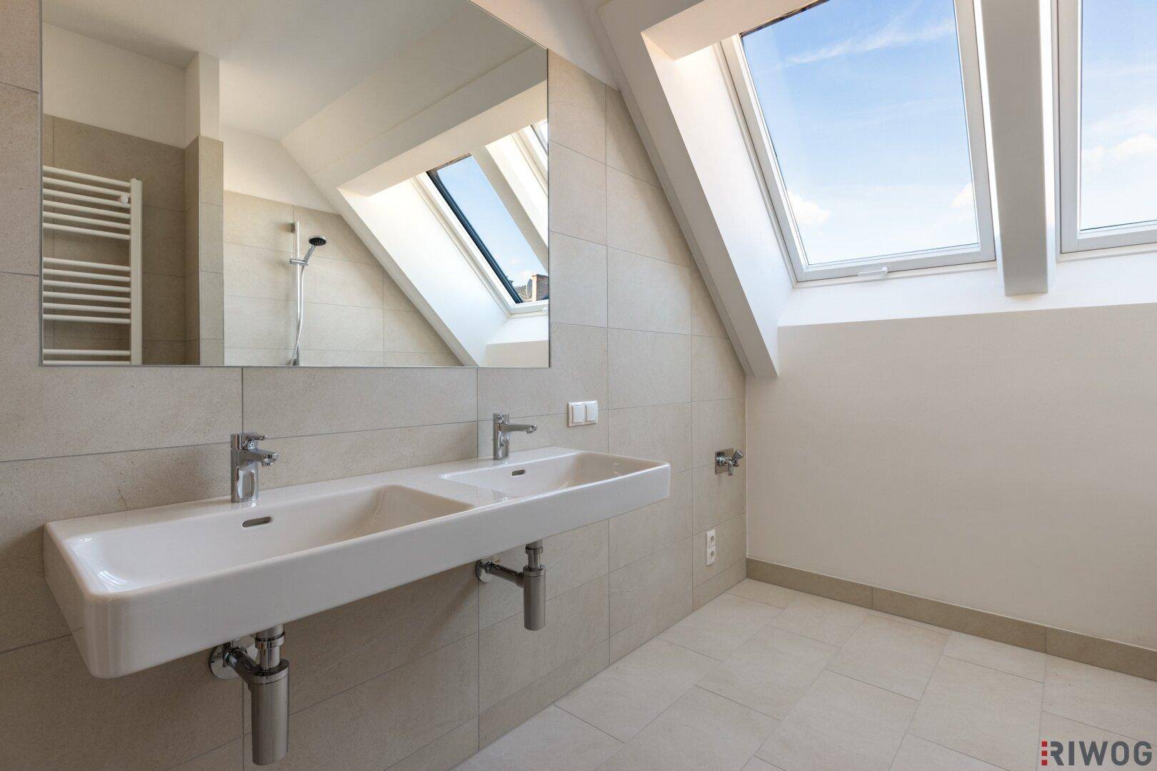 Helles Badezimmer mit Doppelwaschbecken und großem Spiegel, modern gefliest.