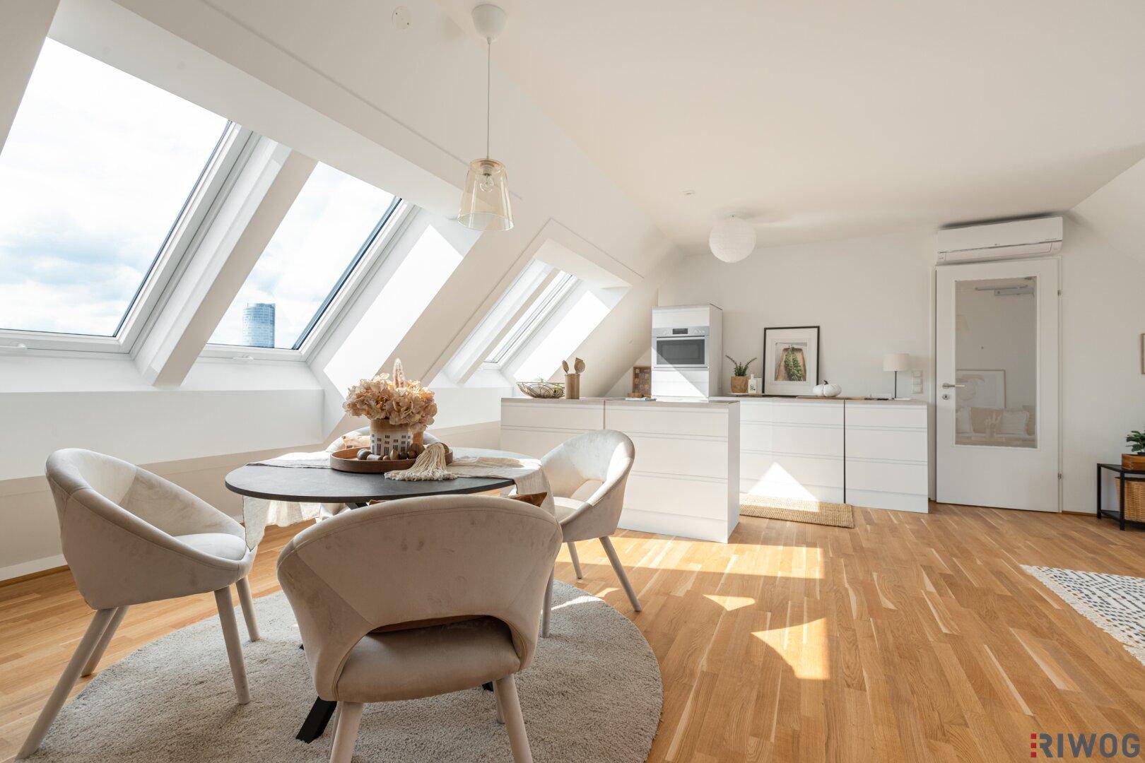Helle Wohnküche im Dachgeschoss mit Holzboden, modernen Einbauten und großen Dachfenstern.