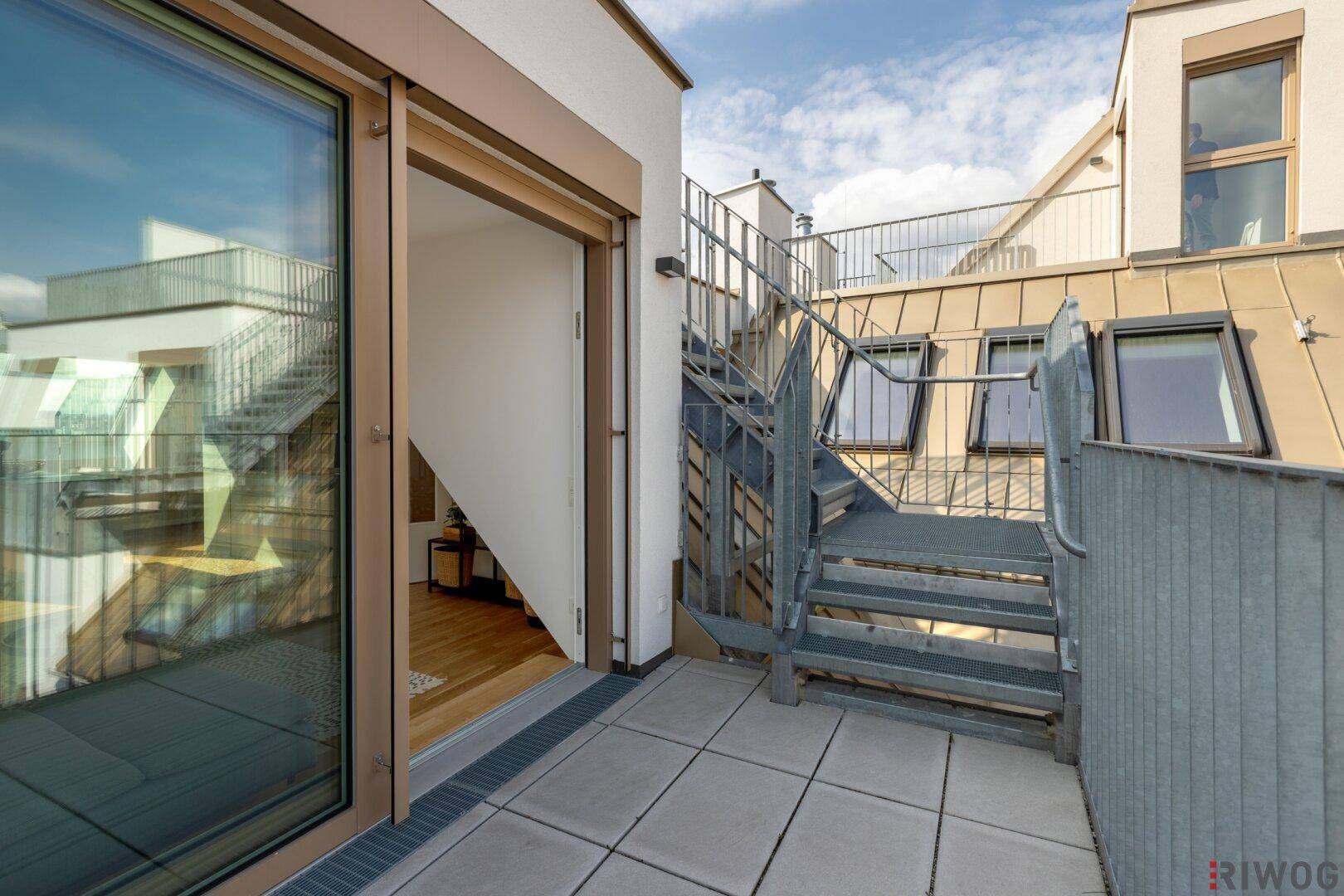Balkon mit Zugang zur Dachterrasse über eine Außentreppe und Blick auf die Umgebung.