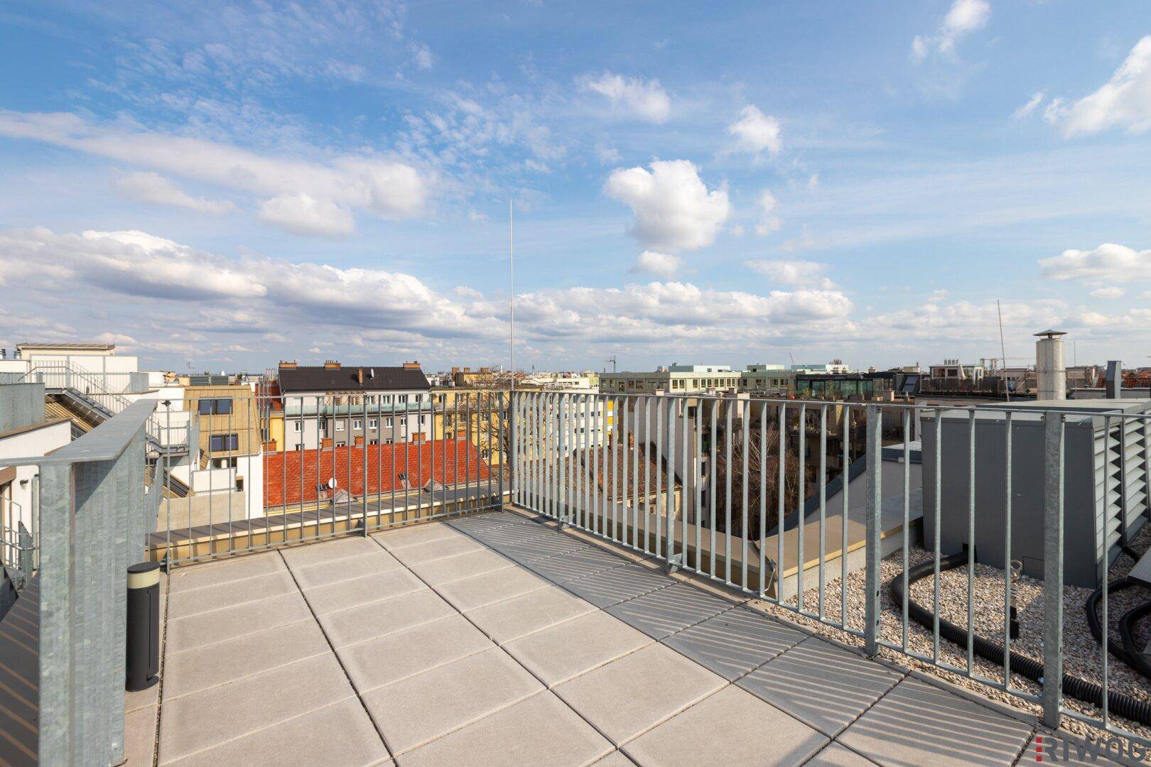 Weitläufige Dachterrasse mit Fliesenboden und Panoramablick über die Stadt.