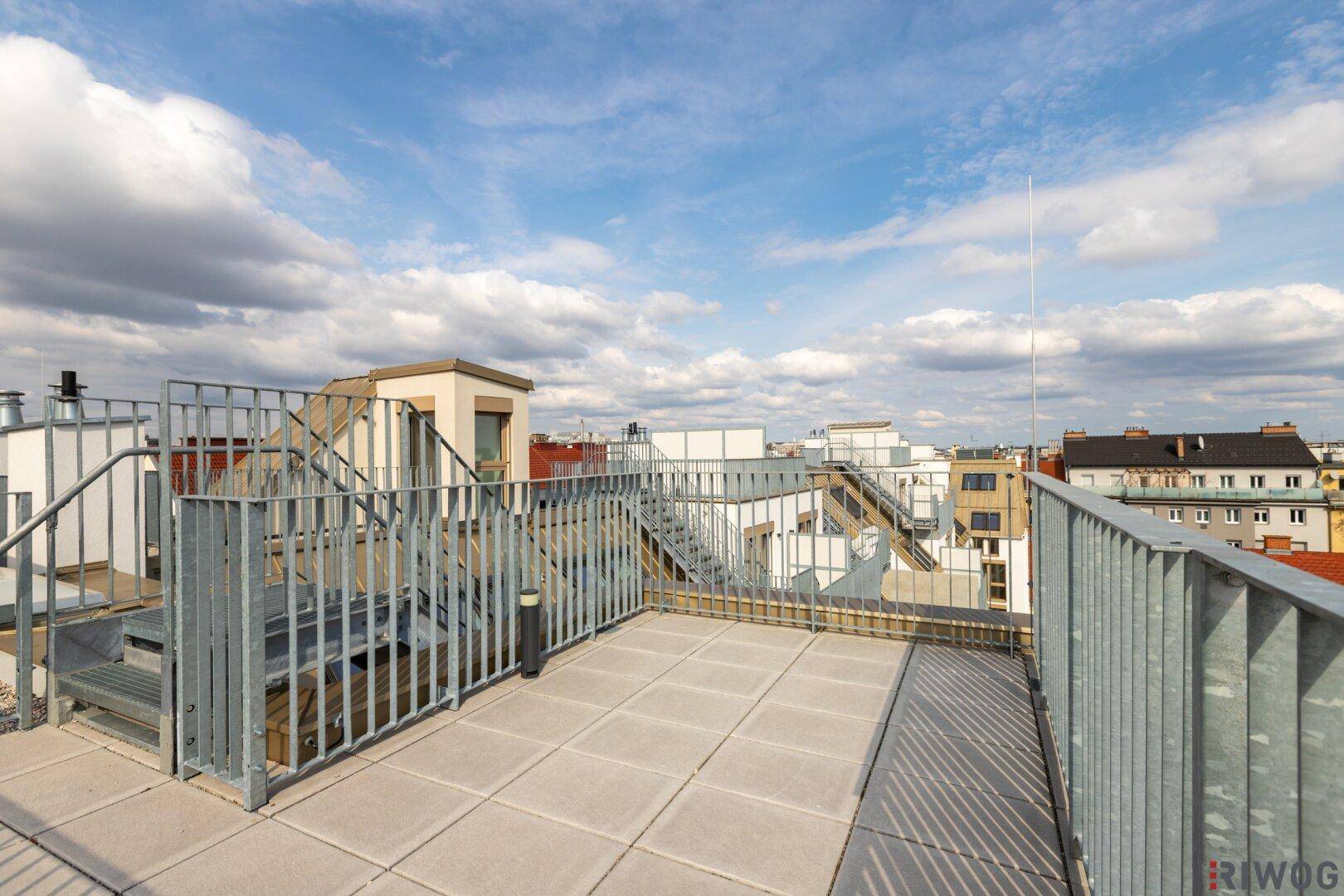 Geräumige Dachterrasse mit Fliesenboden und Treppenaufgang zu einer weiteren Ebene.