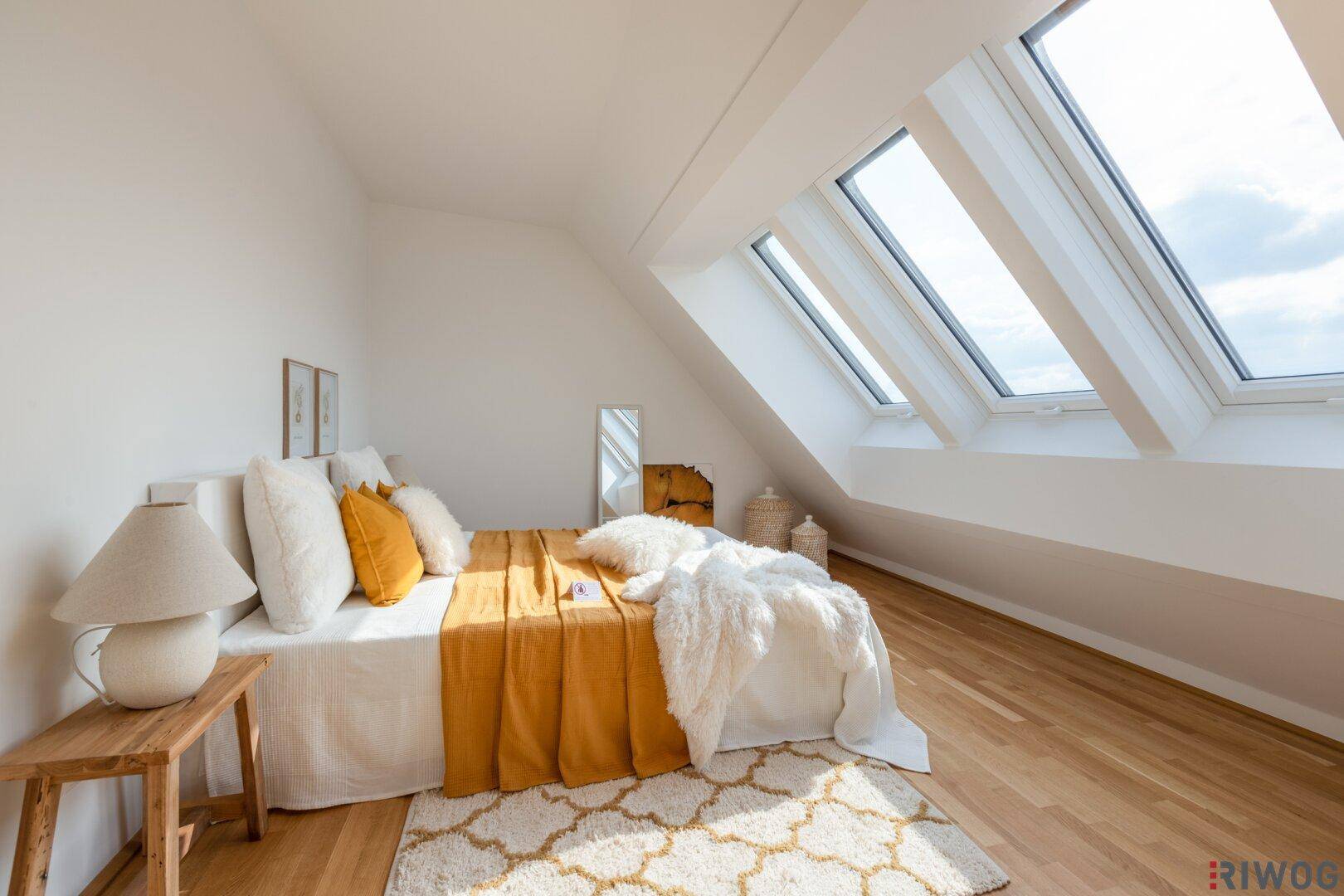 Helles Schlafzimmer im Dachgeschoss mit Holzboden, gemütlichem Bett und großen Dachfenstern.