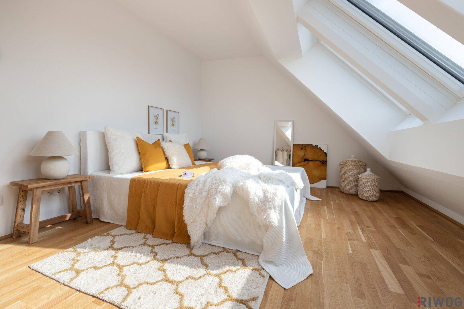 Lichtdurchflutetes Schlafzimmer mit Holzboden, modernem Teppich und schrägen Wänden im Dachgeschoss.