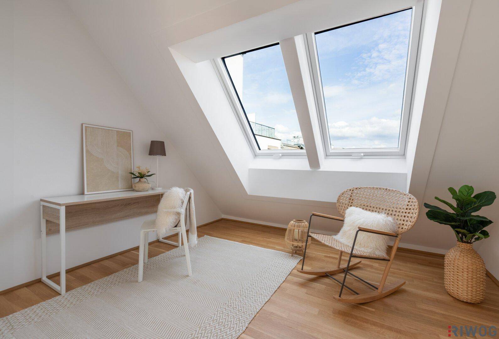 Heller Arbeitsbereich im Dachgeschoss mit Holzboden, Schreibtisch und großen Dachfenstern.