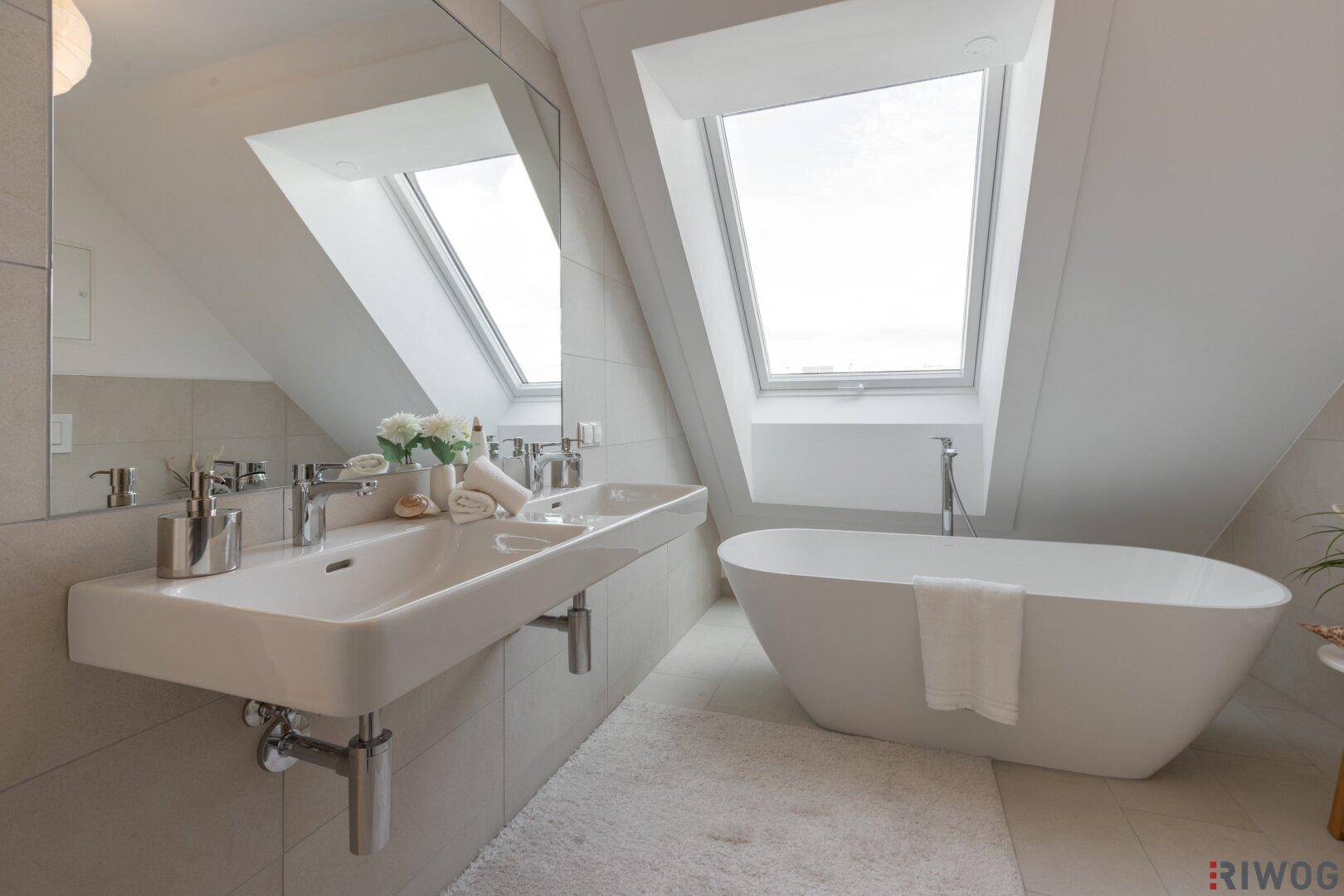Modernes Badezimmer im Dachgeschoss mit freistehender Badewanne, Doppelwaschbecken und Dachfenstern.