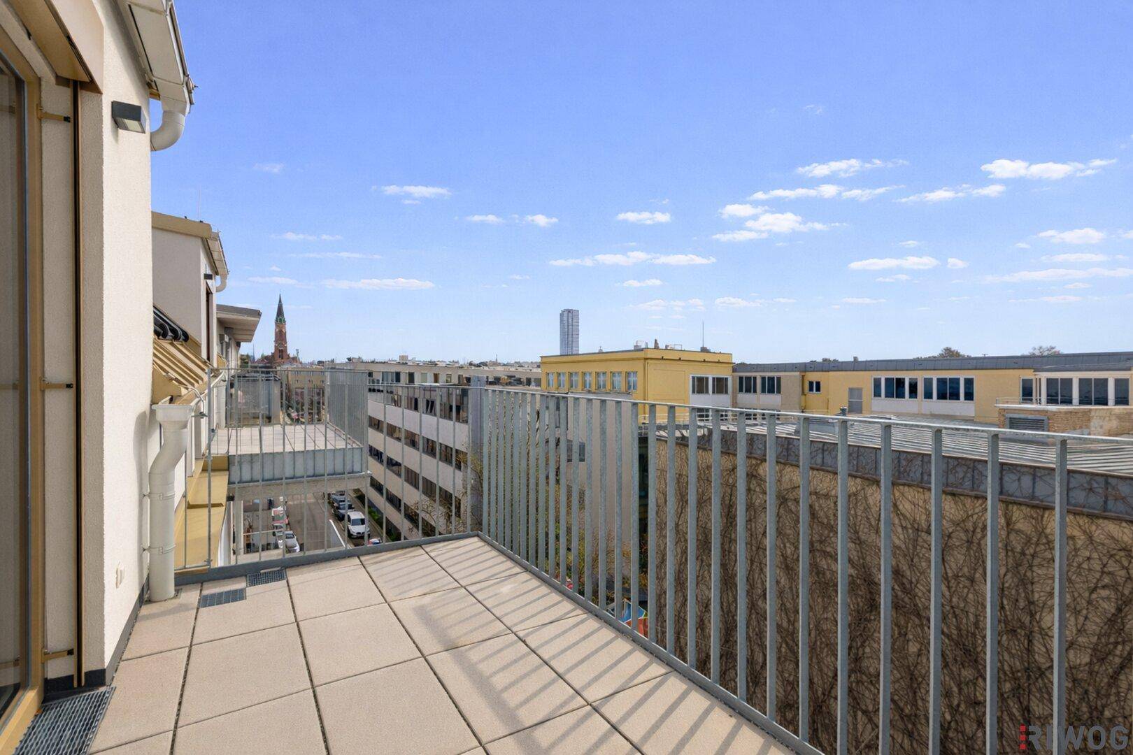 Geräumiger Balkon mit Fliesenboden und Blick auf die umliegende Stadtbebauung.