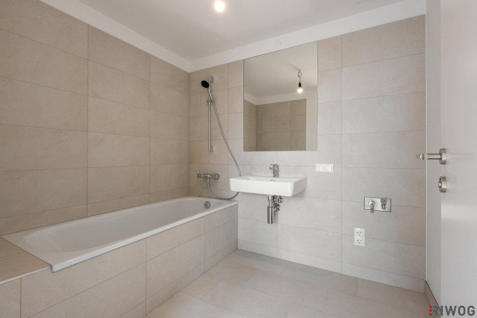 Modernes Badezimmer mit Badewanne, Wandfliesen und einem schwebenden Waschbecken.