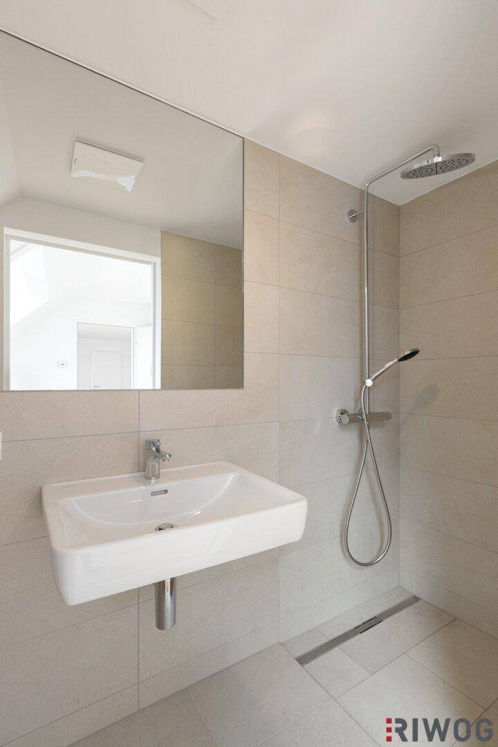 Modernes Badezimmer mit ebenerdiger Dusche, Waschbecken und großem Spiegel.
