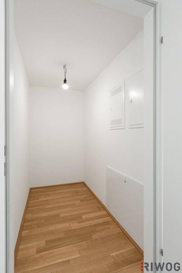 Kleiner, leerer Abstellraum mit Holzboden und weißen Wänden.