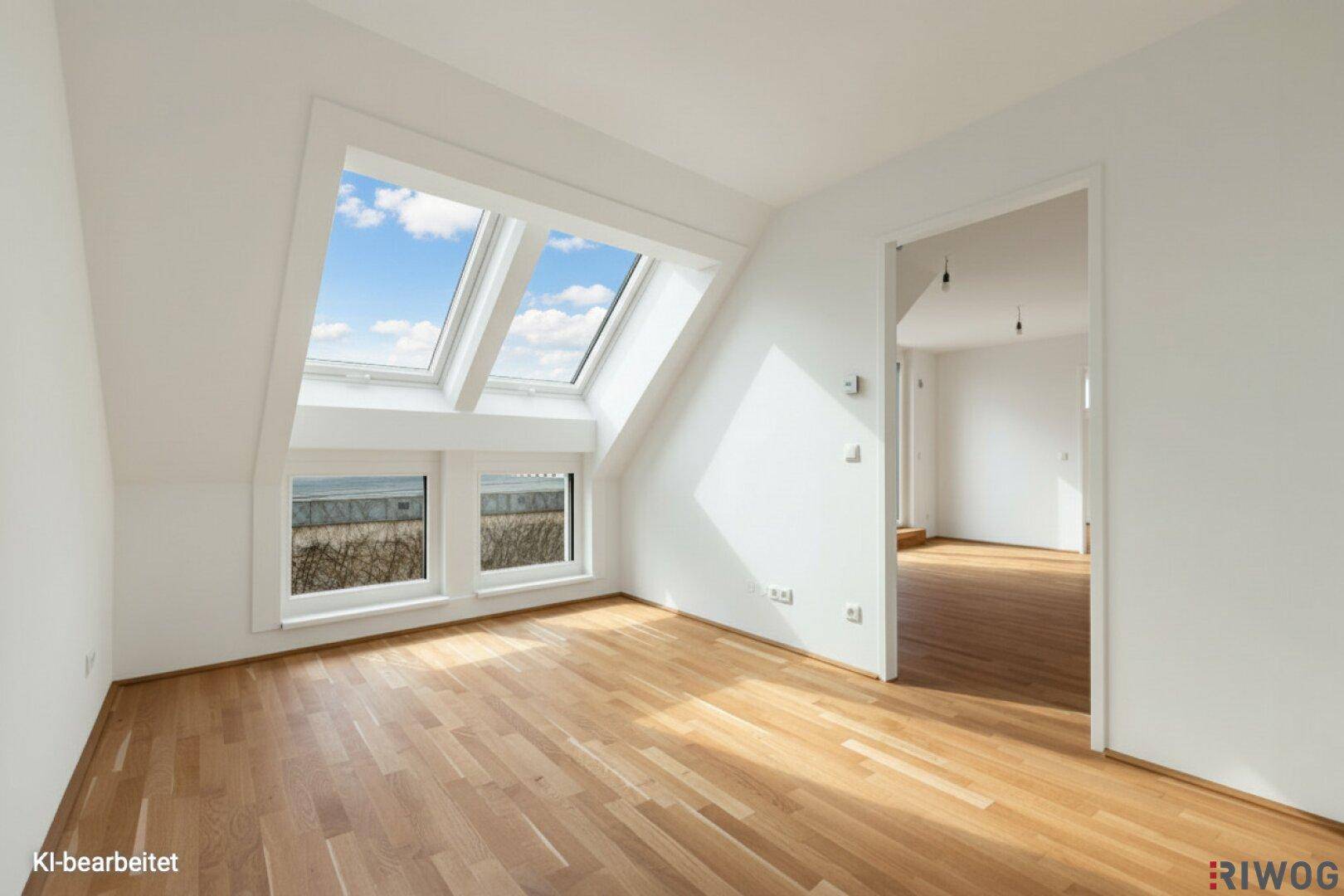 Heller Raum mit Holzboden und großen Dachfenstern, die viel Tageslicht hereinlassen.