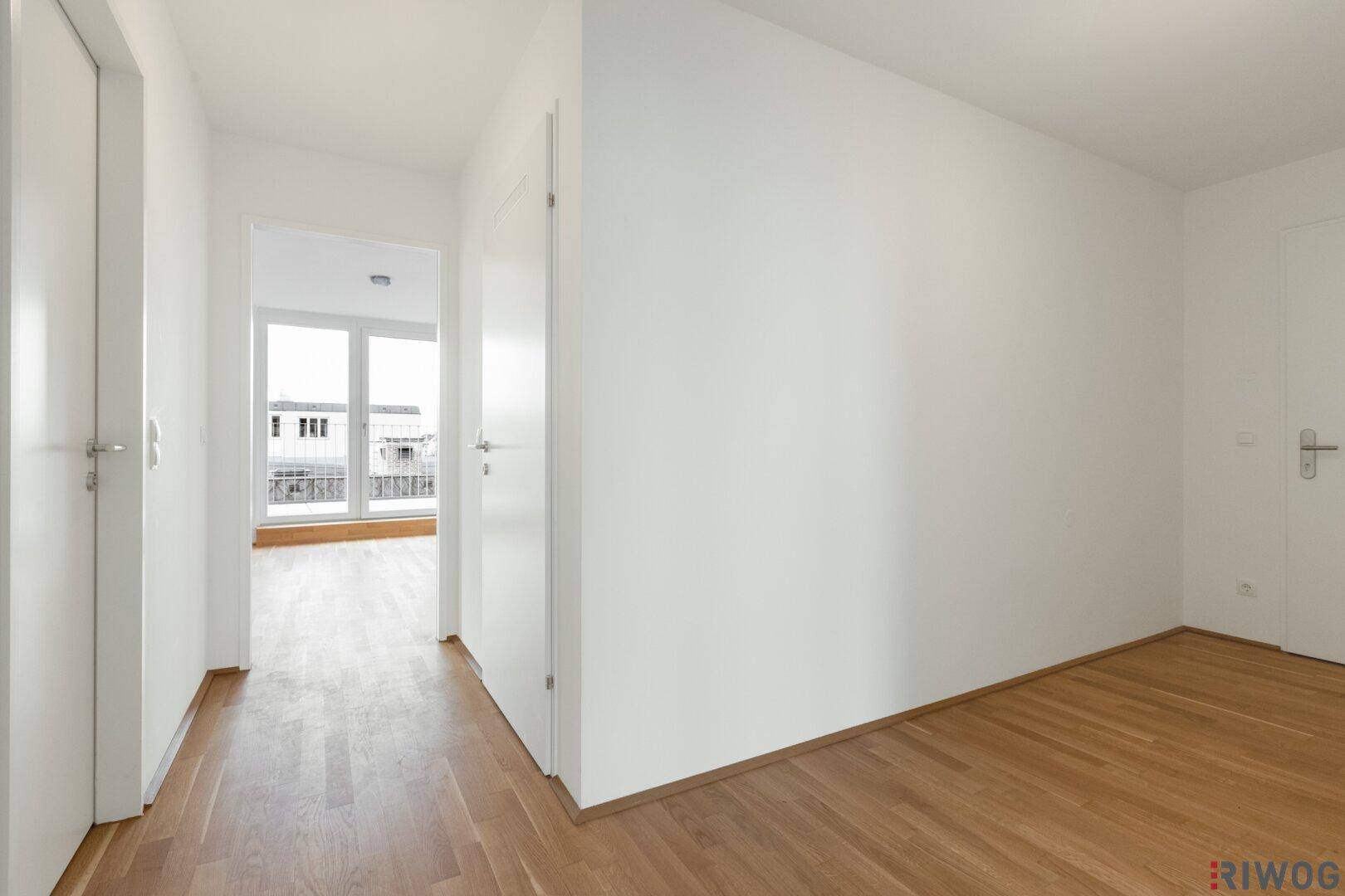 Heller Flur mit Parkettboden und Zugang zu verschiedenen Räumen.