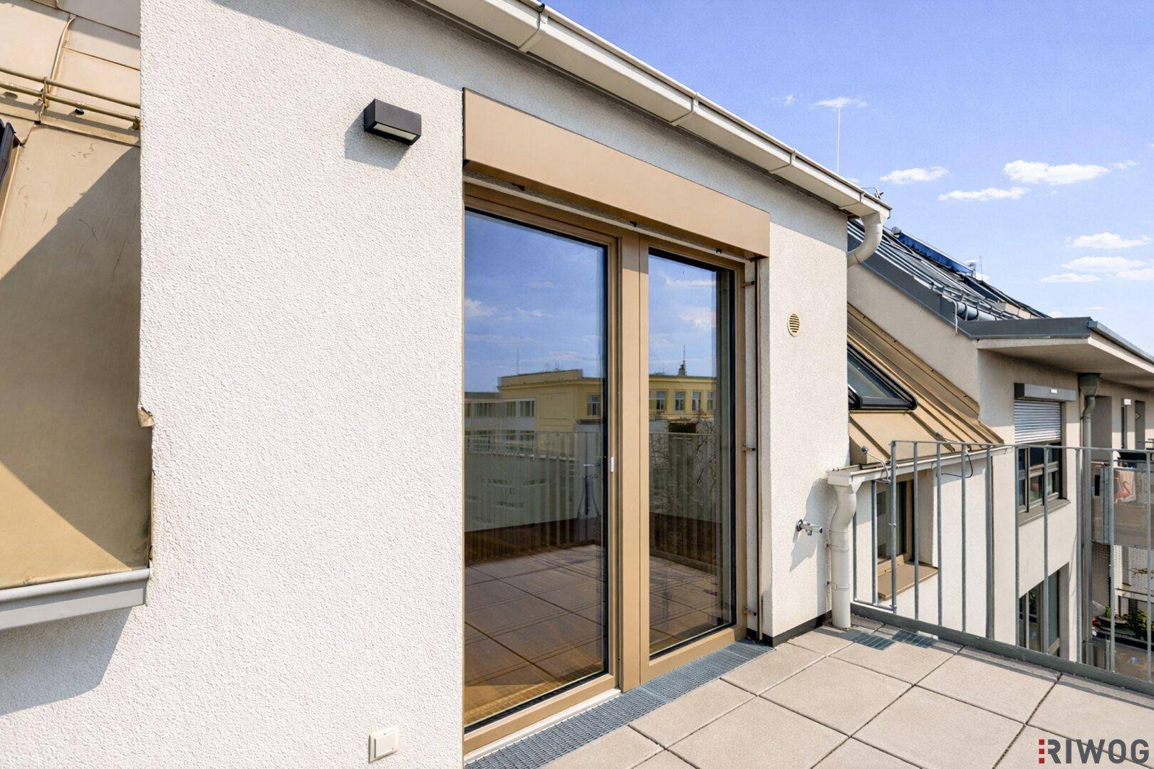 Balkonzugang mit großen Fenstertüren und Blick auf die umliegenden Gebäude.
