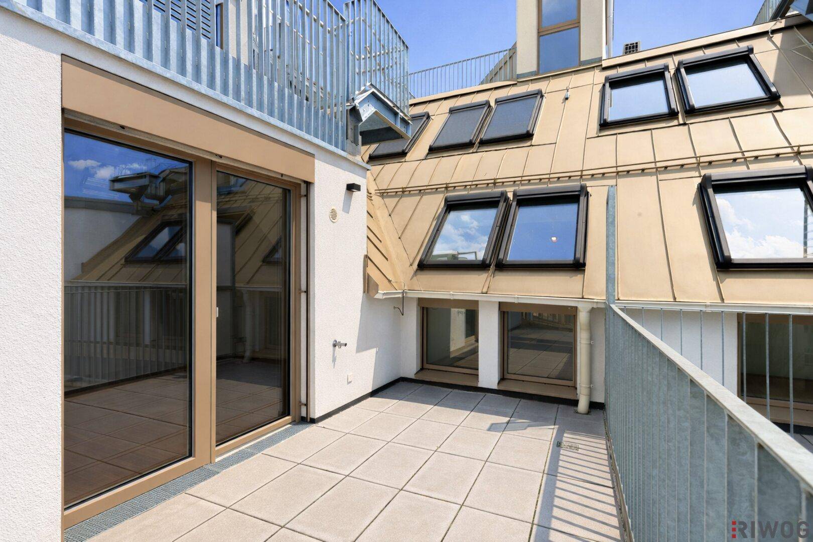 Dachterrasse mit Fliesenboden und Zugang zu weiteren Außenbereichen.