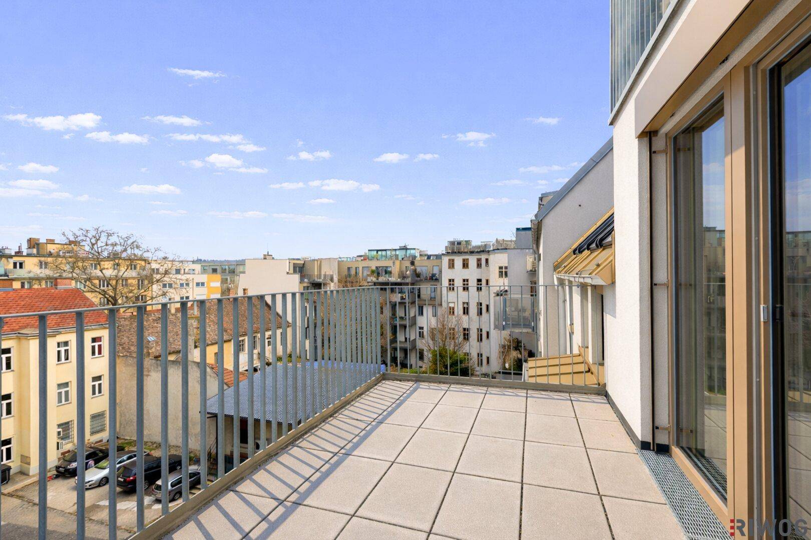 Heller Balkon mit Fliesenboden und weitem Blick über die städtische Umgebung.