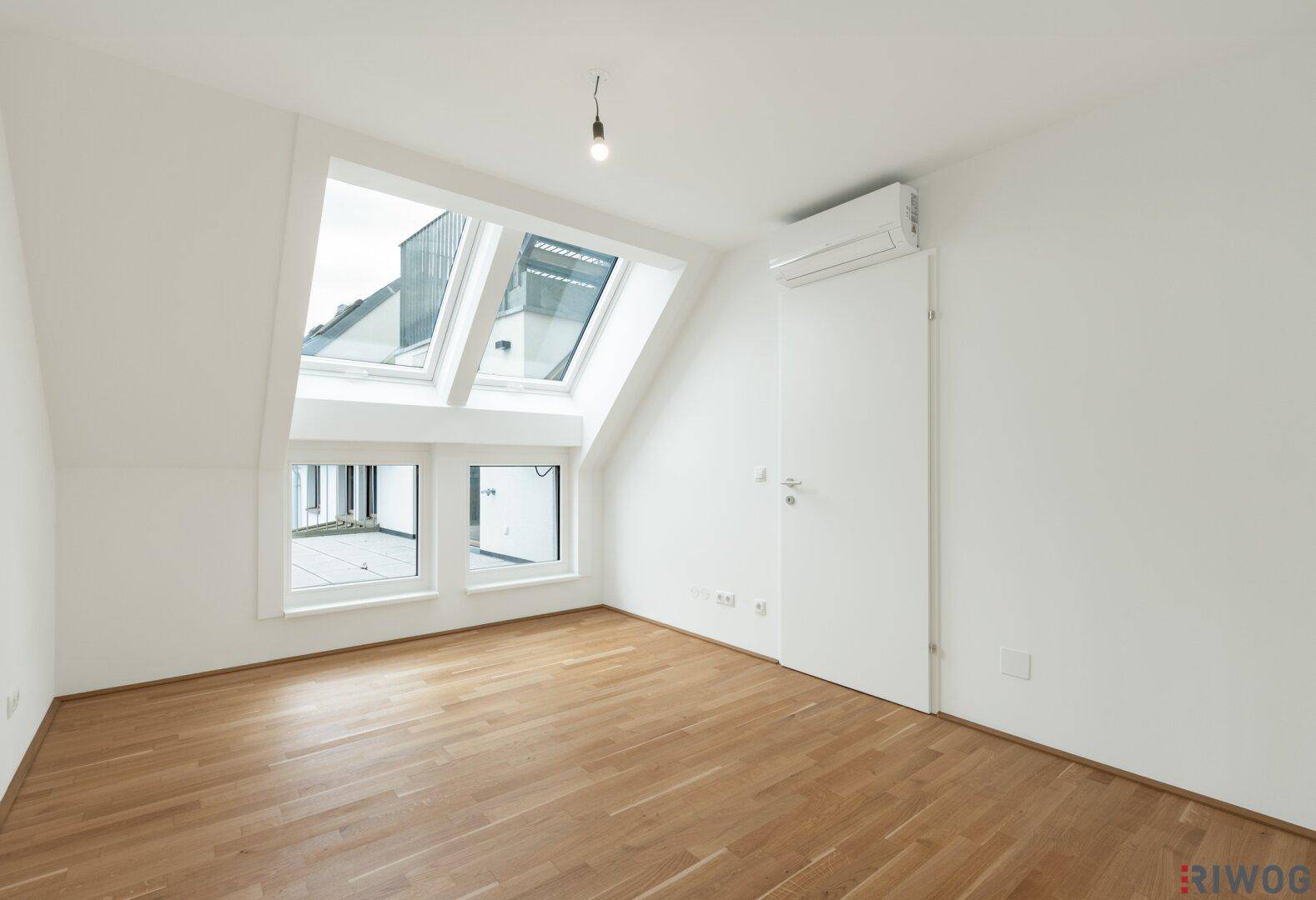 Helles Zimmer mit Parkettboden, Dachfenstern und Klimaanlage.