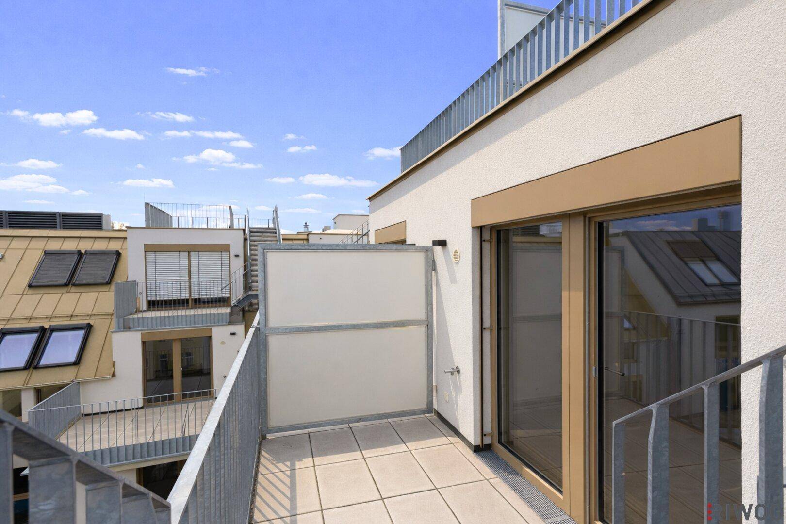 Kleiner Balkon mit Fliesenboden und Blick auf die umliegenden Dächer.