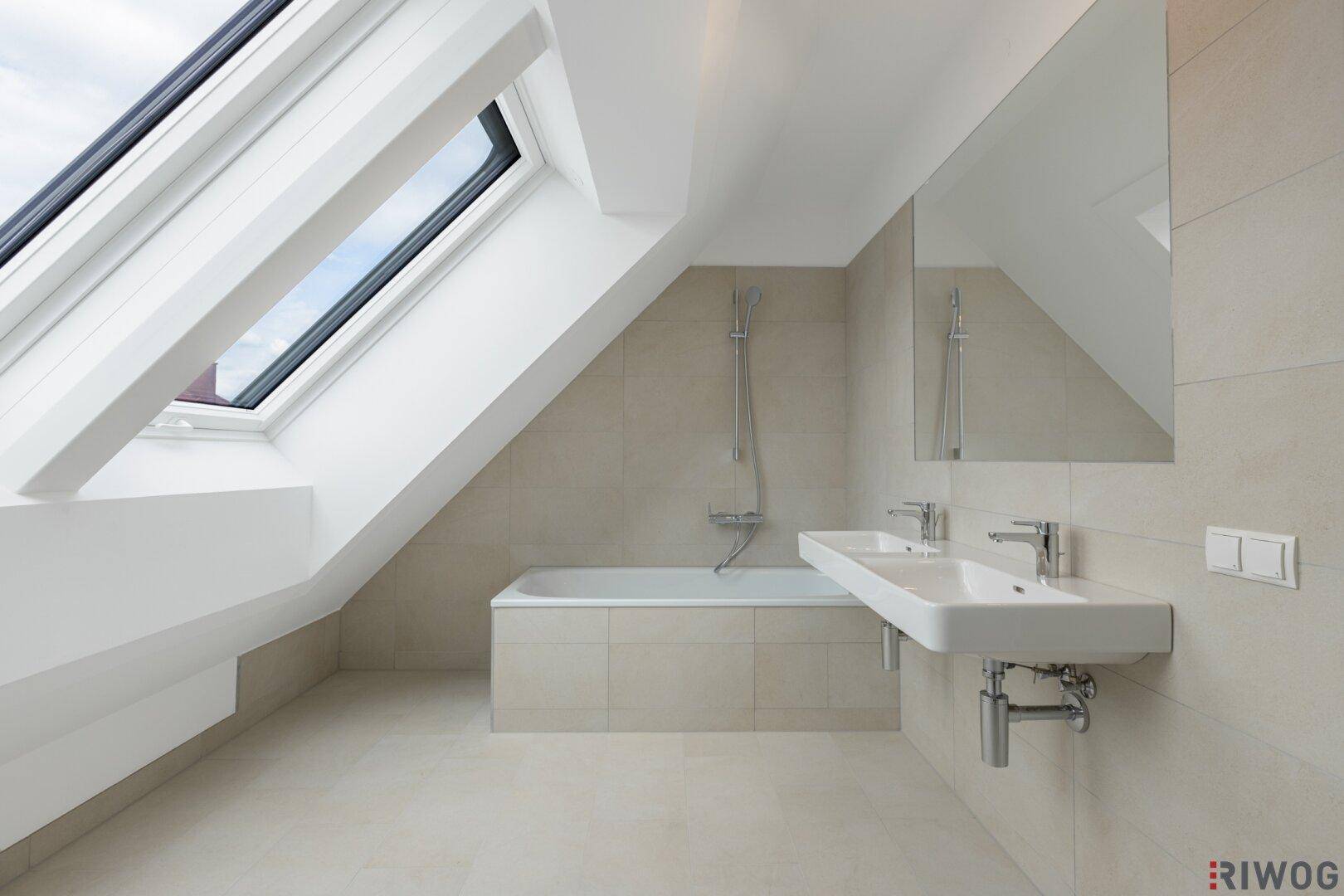 Modernes Badezimmer mit Doppelwaschbecken, Badewanne und Dachfenster.