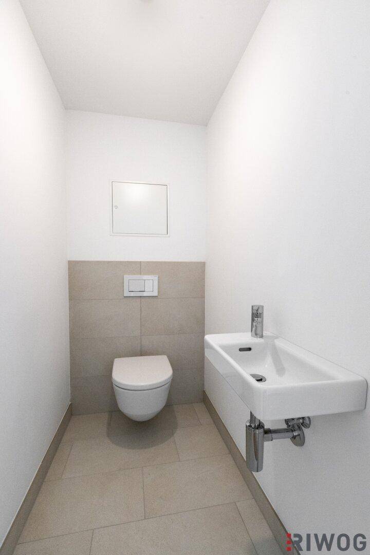 Modernes Gäste-WC mit wandhängender Toilette und kleinem Waschbecken.