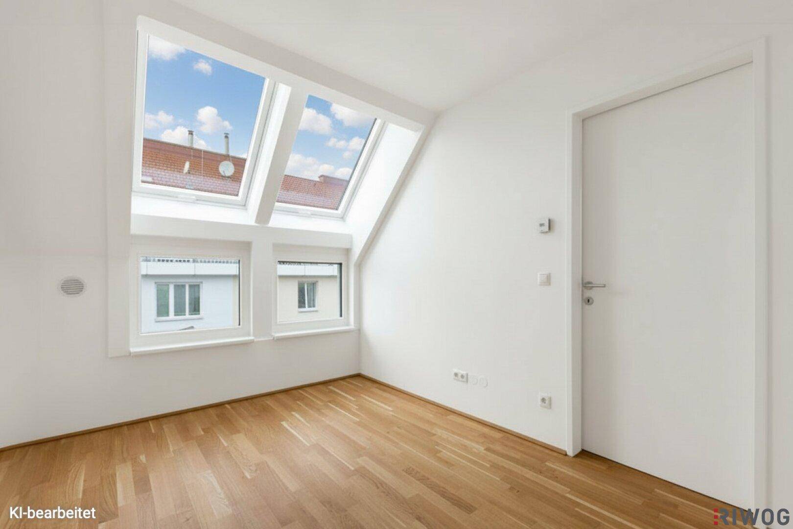 Helles Zimmer im Dachgeschoss mit Parkettboden und mehreren Fenstern.